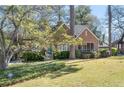 Beautiful brick home with mature trees, green lawn and landscaping, and a screened-in porch at 595 Ridgecrest Ne Rd, Atlanta, GA 30307