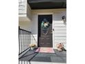 Elegant front door with welcome wreath, potted flowers, and black iron railings at 11250 Bramshill Dr, Johns Creek, GA 30022