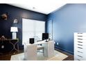 Stylish home office with dark blue walls, a large window, and a contemporary white desk at 7738 Fawn Cir, Covington, GA 30014