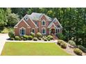 Beautifully landscaped brick home with a well-manicured lawn and mature trees at 2287 Lake Ridge Ter, Lawrenceville, GA 30043