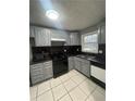 Well-lit kitchen boasts ample gray cabinets, modern black appliances, and sleek black countertops at 4762 Old Highgate Entry, Stone Mountain, GA 30083