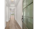 Bright hallway with hardwood floors, white walls, coffered ceiling, and a view to the sunlit living area through glass doors at 1649 Tielman Way, Snellville, GA 30078