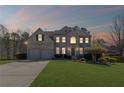 Charming brick two-story home with a well-manicured lawn and a two-car garage at dusk at 330 Meadowcrest Cir, Canton, GA 30115