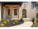 Inviting stone front porch with natural wood supports and arched door at 6055 Tattnall Overlook, Acworth, GA 30101