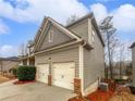 Side view of a two car garage and vinyl siding on a two-story home with a driveway and landscaping at 4963 Arbor View Nw Pkwy, Acworth, GA 30101