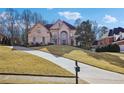 Elegant brick home with a grand entrance, manicured lawn, and a long driveway on a sunny day at 10235 Worthington Mnr, Suwanee, GA 30024