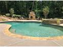 Inviting pool with stone accents, a spa, and an outdoor fireplace, perfect for relaxation and entertaining at 10235 Worthington Mnr, Suwanee, GA 30024