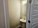 A simple half bathroom with a pedestal sink and a round mirror with a paint grade door and trim at 145 Scarlett Place Dr, Bowdon, GA 30108