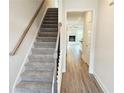 Carpeted staircase leading to the upper level of the house with a view of a living room with a fireplace at 145 Scarlett Place Dr, Bowdon, GA 30108