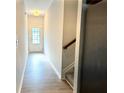 Inviting hallway with wood floors leading to a staircase and a sunlit doorway at 3275 Wild Basil Ln, Buford, GA 30519