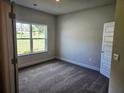 Comfortable bedroom with neutral paint, plush carpet, and a large window overlooking the yard at 112 Scarlett Place Dr, Bowdon, GA 30108