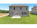 View of the backyard featuring a concrete patio, lush lawn, and neutral-toned exterior siding at 333 Willow Cv, Canton, GA 30114