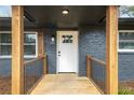 Inviting entryway showcasing a modern white door with glass panes, framed by wooden pillars and a charming wooden porch at 465 Hurt Se Rd, Smyrna, GA 30082