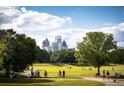 A park with walking path, green lawn, mature trees, and city skyline in the background at 330 9Th Ne St # 11, Atlanta, GA 30309