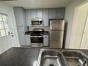 Kitchen boasts stainless steel appliances with gray painted cabinets and dark countertops at 251 Margaret St, Fairburn, GA 30213