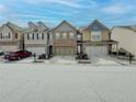 View of a row of townhomes, each with unique architectural details and individual garages at 3318 Sardis Bend Dr, Buford, GA 30519