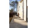 A view of the side of the home, showing the lawn and the exterior facade with a long, concrete walkway at 793 Round Tree Ct, Lawrenceville, GA 30045