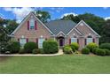 Charming brick home featuring a well-manicured lawn, red shutters, and beautiful landscaping at 8008 Revere Dr, Mcdonough, GA 30252
