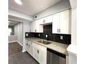 Well-lit kitchen showcasing white cabinets, black backsplash and stainless steel dishwasher at 1502 Huntingdon Chase, Atlanta, GA 30350