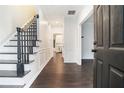 Bright foyer with hardwood floors, elegant staircase, and white wainscoting, leading to the kitchen area at 725 Victoria Station Blvd, Lawrenceville, GA 30043