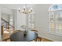 Bright dining room showcasing modern chandelier, wood floors, wainscoting, and window shutters, offering a comfortable ambiance at 11745 Windbrooke Way, Johns Creek, GA 30005