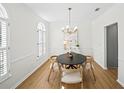 Elegant dining room featuring a modern chandelier, light wood floors and white wainscoting, enhancing the space at 11745 Windbrooke Way, Johns Creek, GA 30005