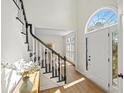 Bright foyer showcasing a staircase with black and white accents, light wood flooring, and an arched window door at 11745 Windbrooke Way, Johns Creek, GA 30005