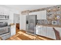 Bright kitchen with white cabinets, stainless steel appliances, and stylish wallpaper at 3619 Spring Leaf Ln, Acworth, GA 30101