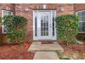 Close-up of a white front door with sidelights, framed by green bushes and red mulch at 504 Trotters Ln, Mcdonough, GA 30252