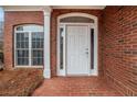Close-up of a classic white front door with sidelights and a brick facade at 1550 Woodberry Run Dr, Snellville, GA 30078