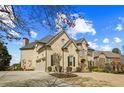 Elegant brick home with a three-car garage and meticulously maintained landscaping on a sunny day at 2088 Skybrooke Ct, Hoschton, GA 30548