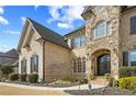 Close-up of a brick and stone home featuring an arched doorway and manicured landscaping at 2088 Skybrooke Ct, Hoschton, GA 30548