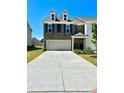 Charming two-story townhome features a gray brick facade, well-maintained lawn, and a three car garage at 2560 Quarterdeck Dr, Cumming, GA 30041