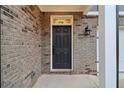A close up of the front entry featuring a dark door surrounded by brick and a classic lantern at 5384 Heron Bay Blvd, Locust Grove, GA 30248