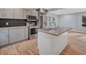 Open-concept kitchen with stainless steel appliances, gray cabinets, and a granite island at 2195 Burroughs Ave, Atlanta, GA 30315