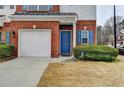 Close up of a brick townhome with blue front door, garage and landscaped yard at 83 Brookway Trce, Norcross, GA 30071