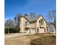 Side view of a two-story home, showcasing attached garage, stucco exterior, and mature trees at 607 Delphinium Nw Blvd, Acworth, GA 30102