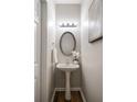 Powder room featuring a pedestal sink, oval mirror, and soft lighting, complemented by stylish flooring at 1096 Liberty Nw Pkwy, Atlanta, GA 30318