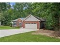 A single-Gathering home has a two-car garage, a lawn, and many trees surrounding the home at 4125 Gables Pl, Buford, GA 30519
