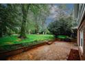 Backyard brick patio with a lush lawn and mature trees, perfect for outdoor entertaining or relaxing in a serene setting at 4144 Hideaway Dr, Tucker, GA 30084