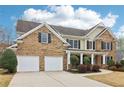Stately brick residence featuring a two-car garage, manicured landscaping, and a covered front porch at 6945 W Mountain Xing, Cumming, GA 30041