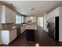 Well-equipped kitchen features stainless steel appliances, an island with granite countertops, and white cabinetry at 6945 W Mountain Xing, Cumming, GA 30041