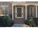 Inviting entryway with brick steps, decorative columns, and a dark, paneled front door at 1615 Chattahoochee Run Dr, Suwanee, GA 30024