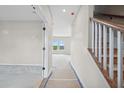 Bright hallway featuring staircase with wooden handrail and large windows at the far end at 61 Okeechobee Way, Braselton, GA 30548