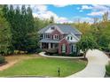 Two-story home boasts a beautiful lawn, landscaping, and a long driveway amid a lush and private wooded property at 203 Glenrise Ct, Woodstock, GA 30188