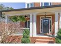 Inviting front porch with brick accents, classic columns, ferns, and a decorative wreath on the door at 112 Bluestone Ct, Acworth, GA 30101