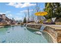 Stunning pool area featuring stone accents, cascading waterfalls, and lounge chairs under a yellow umbrella at 3323 Acorn Falls Dr, Marietta, GA 30062