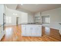 Open kitchen with island cooktop, white cabinets, hardwood floors, and a view to the living space at 3968 Belle Glade Ct, Snellville, GA 30039