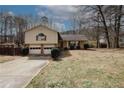 Charming tan home with a two-car garage with a well-maintained lawn and mature trees at 4161 Windermere Dr, Lithonia, GA 30038