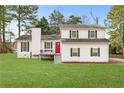 Charming two-story home features a red front door, green lawn, and traditional shutters at 712 Berts Nw Cir, Lilburn, GA 30047